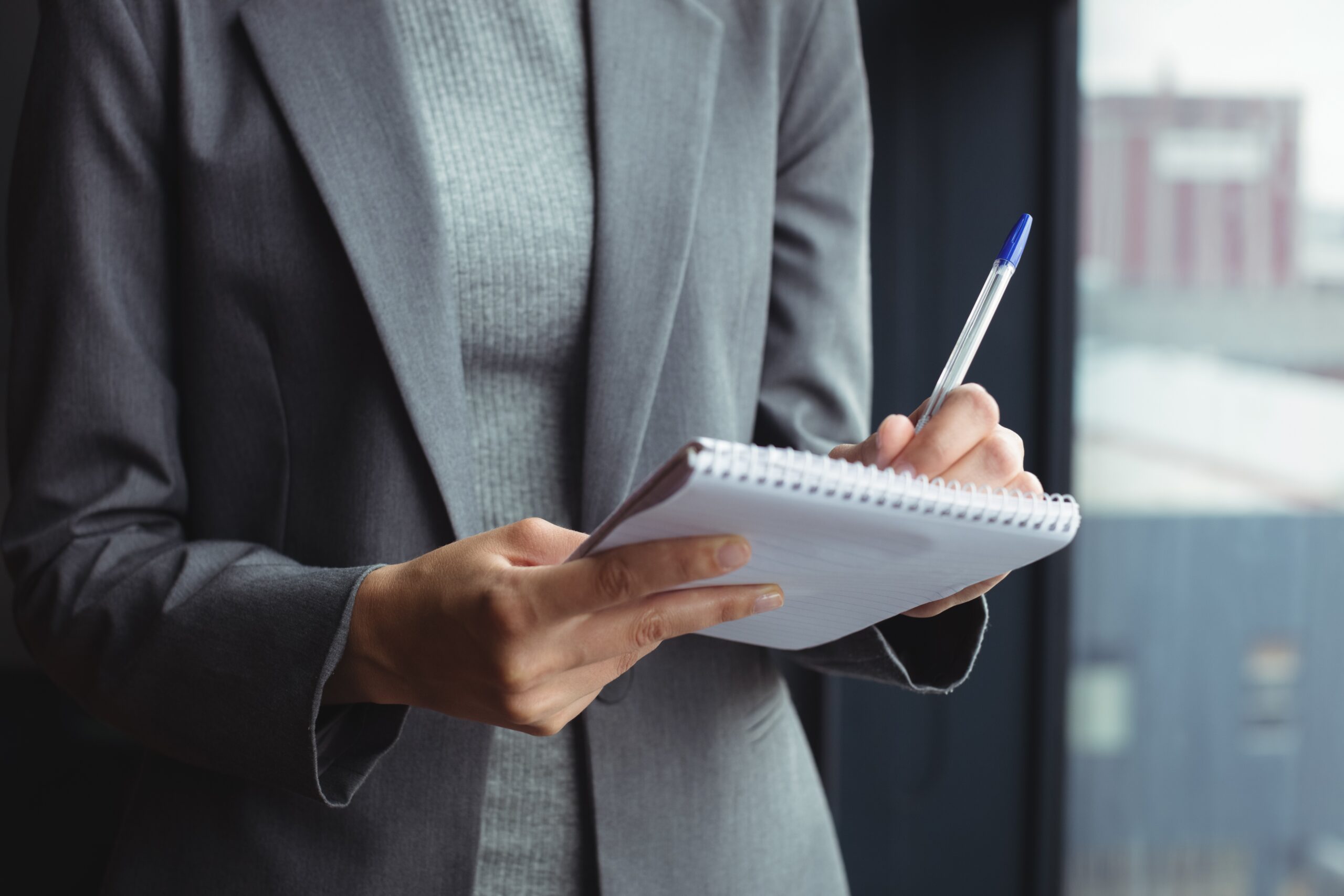 person taking notes on paper with a pen