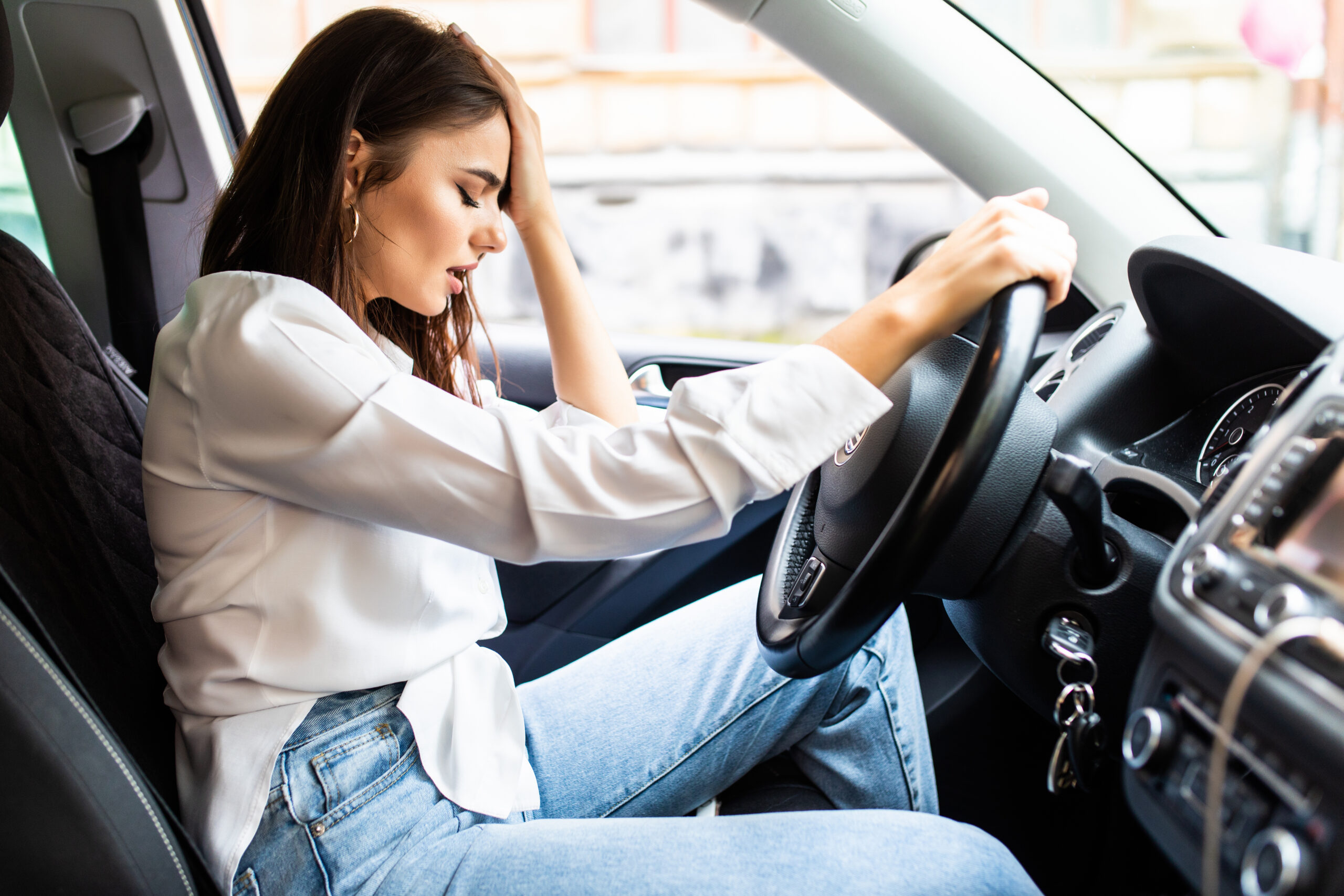 Young sad woman driver in car on the street