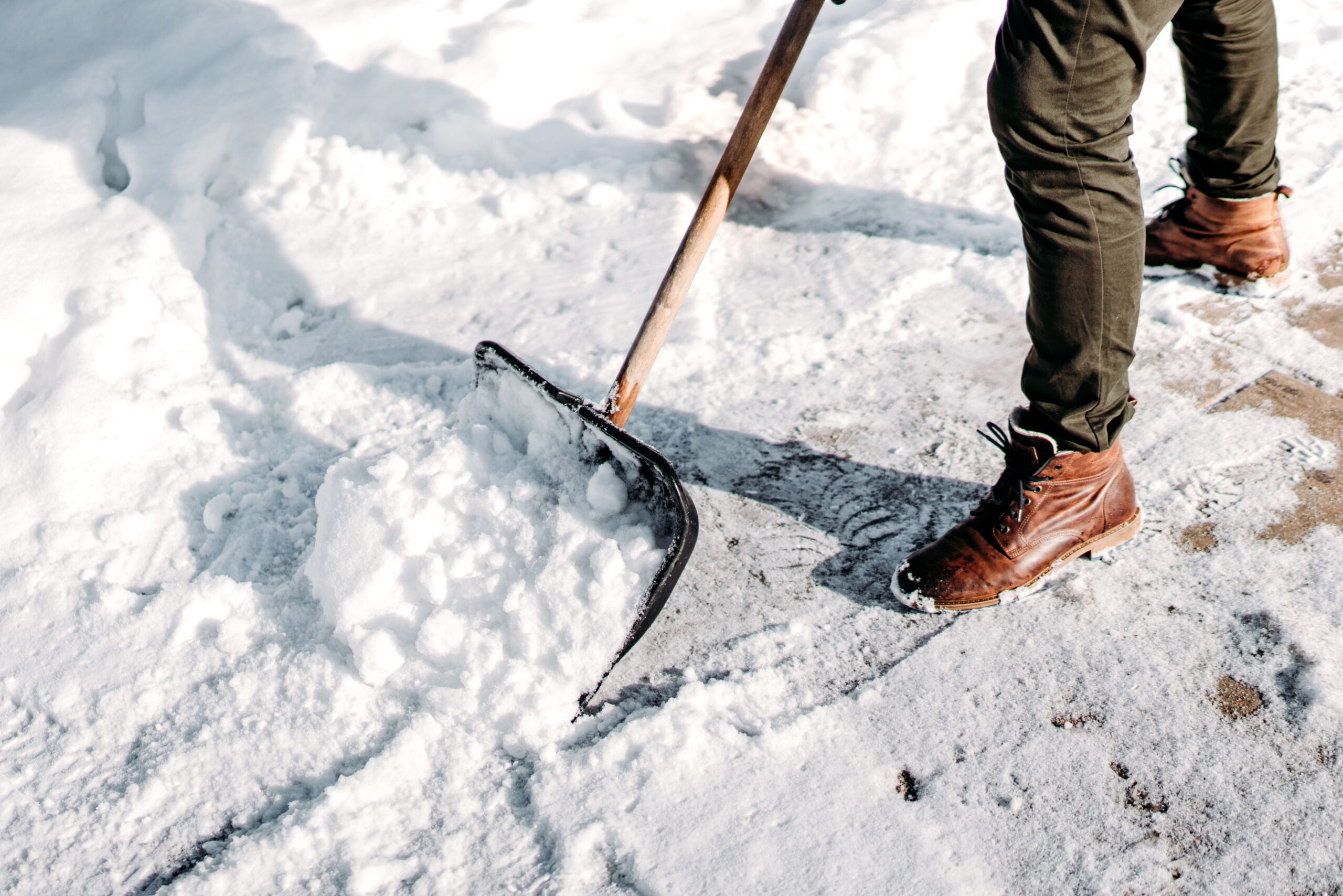 Man cleaning snow from house alley. Details of male using snow shovel